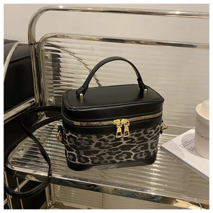 Detail of leopard print bucket bag with gold zippers and black leather top handle