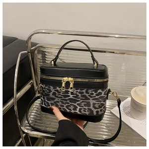 Détail du sac seau à imprimé léopard avec finitions en cuir noir et boucles dorées
