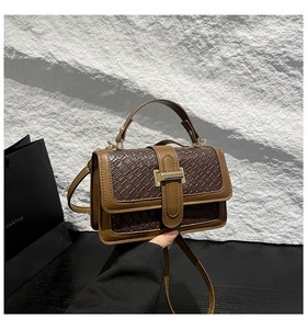 Detail of contrast color crossbody bag with woven texture and vintage gold buckle