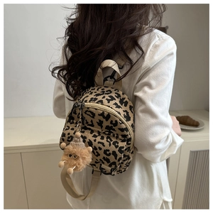 Detail of leopard print mini backpack with brown bear plush keychain and adjustable straps