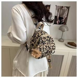 Close-up of leopard print mini backpack with plush brown charm and adjustable strap