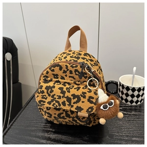 Detail of trendy leopard print corduroy mini bag with a plush monster charm on a table