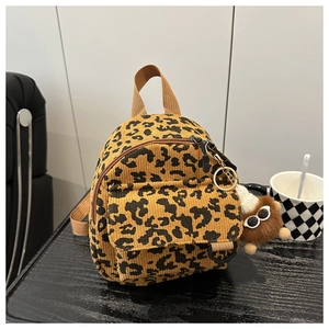 Close-up of leopard print corduroy mini bag with a plush charm on wood background