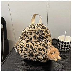 Detail of leopard print corduroy mini backpack with small plush monster charm accessory