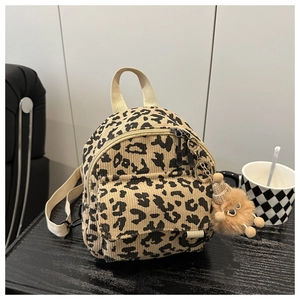 Detail of leopard print corduroy mini bag with plush monster charm on black table