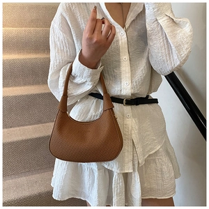 Close-up of a brown woven hobo bag with minimalist half-moon shape and shoulder strap