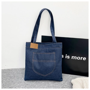 Détail du sac cabas en denim avec coutures jaunes et écusson en cuir marron