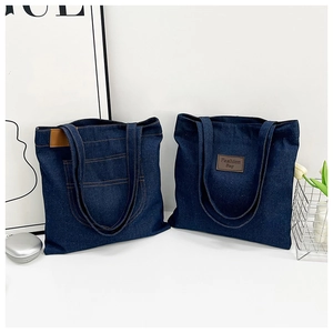 Détail de grands sacs fourre-tout en denim avec étiquettes en cuir et poches cousues