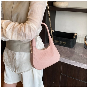 Detail of pink woven crescent bag with gold chain strap shown in a lifestyle setting