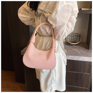 Detail of pink woven texture crescent bag with gold chain strap on a white dress