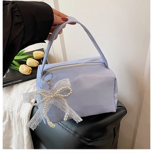 Detail der hellblauen Handtasche mit Perlenspitzen-Bogen-Anhänger und stabilem Griff