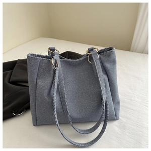 Detail view of large grey striped tote bag with gold metal rings and denim texture