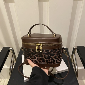 Leopard print bucket bag with dual zippers and gold hardware on vintage background