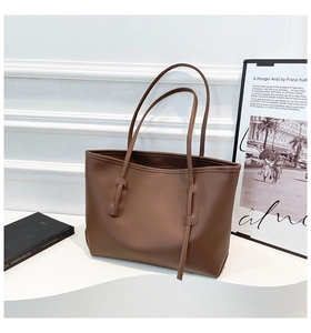 Macro detail of dark brown tote bag showing smooth leather texture and strap attachment