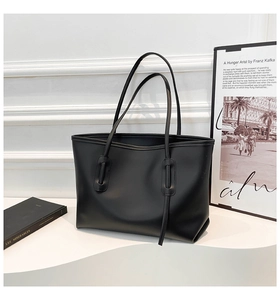 Detail of black faux leather tote bag with unique strap eyelets and minimalist design