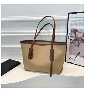 Detail of minimalist tote bag with beige body and contrasting dark brown handles