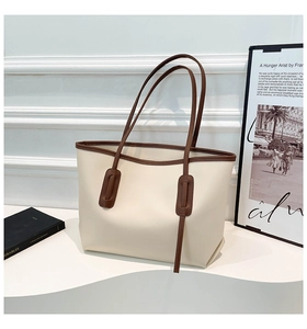 Detail of minimalist cream tote bag with contrast brown straps and modern buckle decor