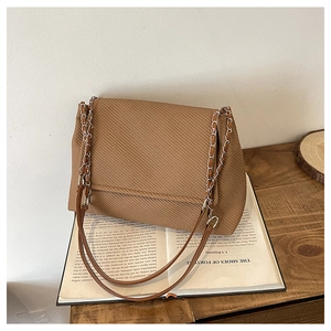 Detail einer braunen Cord-Tragetasche mit Kettenriemen und Vintage-Klappenverschluss
