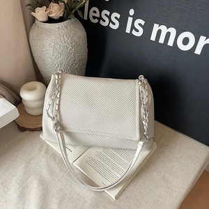 Schicke weiße Tote-Bag mit Litschi-Struktur und Silberkette auf minimalistischem Buch