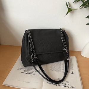 Schicke schwarze strukturierte Tragetasche mit silberner Kette auf minimalistischem Magazin