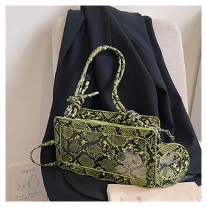 Macro detail of a neon snake-pattern handbag with a woven handle and mini round coin purse
