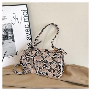 Detail of snakeskin print crossbody bag with wave edge and round coin purse attachment