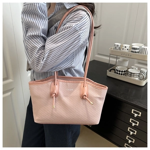 Pink oil wax leather tote bag shown on shoulder featuring elegant knot details and texture