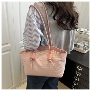 Pink knit tote bag detail with long shoulder strap and knot decoration on a model