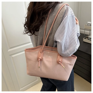 Side view of a pink textured tote bag worn by a model to show size and shoulder fit