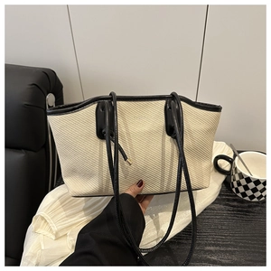 Detail of the woven texture and contrast black faux leather trim on the tote bag
