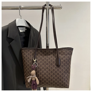 Detalle de un bolso tote marrón con monograma de letra M, correas de cuero y colgante de conejo