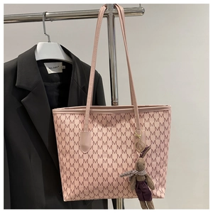 Detalle de bolso tote rosa con estampado de letras, colgante de conejo y correa fina
