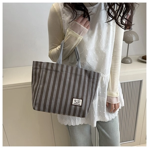 Detailed close-up of vertical striped canvas tote bag with Camping fabric patch