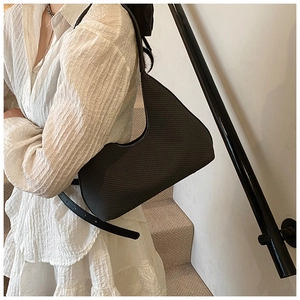 Detail of a dark woven Hobo bag showing the intricate texture and minimalist crescent shape