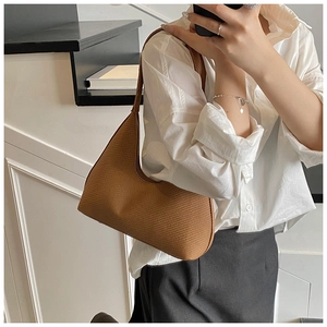 Mirror selfie showing the brown woven leather hobo bag worn as an elegant underarm bag