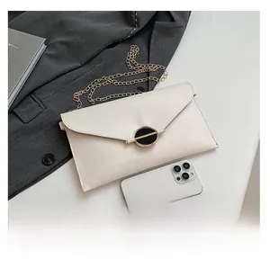 Gros plan de la pochette enveloppe blanche avec bandoulière chaîne et comparaison de taille