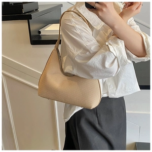 Gros plan du sac hobo tissé beige avec fermeture éclair et pieds de protection en métal