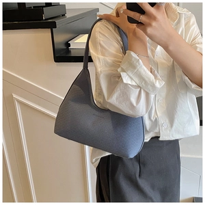 Close-up of blue woven texture shoulder bag with zipper closure and slim strap details