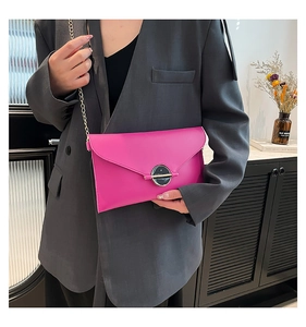 Gros plan d'un sac enveloppe rose avec chaîne dorée sur un blazer gris chic