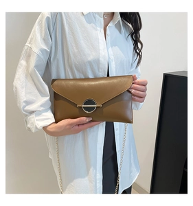 Détail d'un sac bandoulière marron caramel avec chaîne dorée et boucle métallique