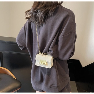 Détail d'un mini sac à bandoulière blanc crème avec chaîne dorée et fermoir rotatif