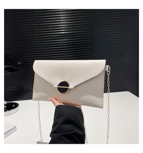 Vue détaillée du sac enveloppe blanc cassé avec chaîne dorée et fermoir rond élégant