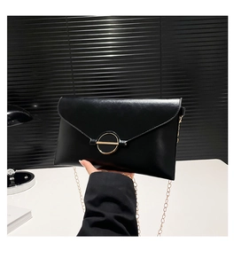 Détail du sac à main enveloppe noir avec boucle dorée et bandoulière en chaîne
