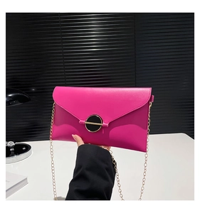 Détail du sac enveloppe rose avec une grande boucle dorée et une bandoulière chaîne