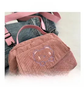 Macro view of pink corduroy fabric and cute bear embroidery on the small messenger bag