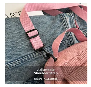 Detail of pink corduroy crossbody bag showing adjustable strap and black hooks