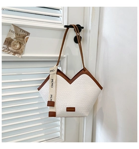 Close-up of white crocodile pattern tote bag with brown handles and V-shaped design