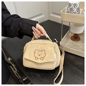 Close-up of beige corduroy crossbody bag featuring cute brown bear embroidery detail