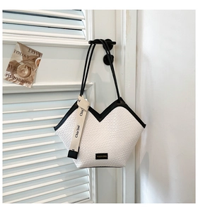 Detailed view of woven texture tote bag with letter strap on white shutters