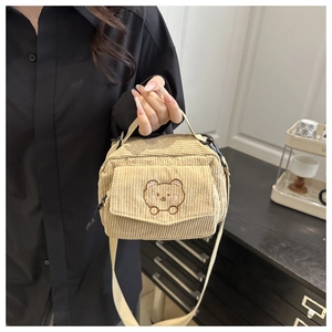 Detailed texture of beige corduroy crossbody bag featuring a cute brown bear embroidery